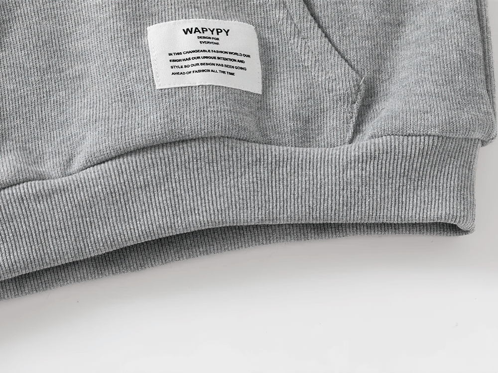 Close-up of a gray fleece-lined kid's sweatshirt with pocket and label, ideal for boys and girls, featuring white stripes on the sleeves.